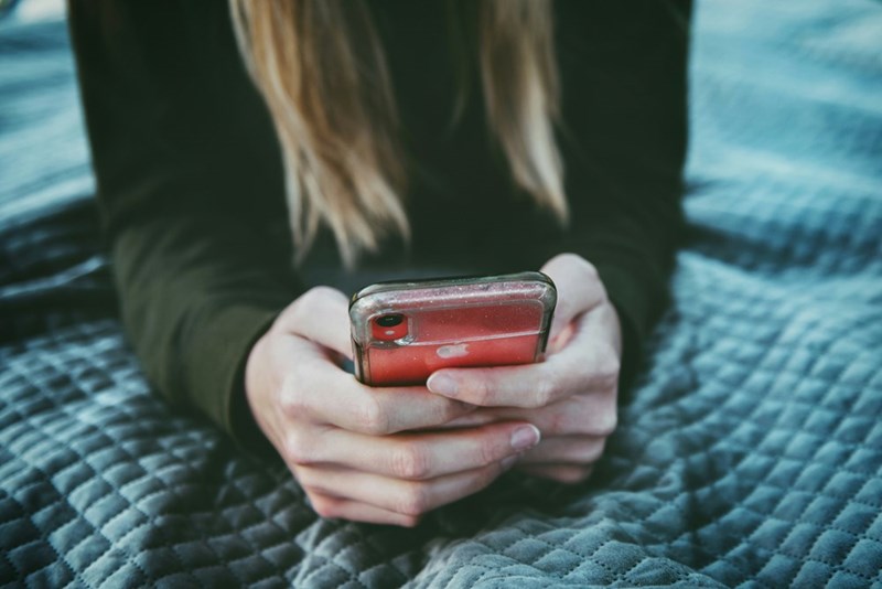 A woman holds a silver and red phone in her hands