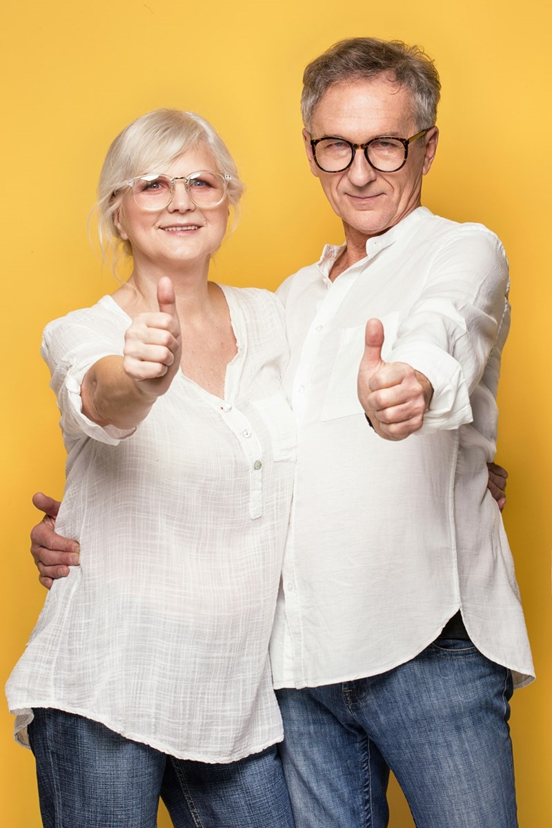 An older happy couple excitedly give the thumbs up