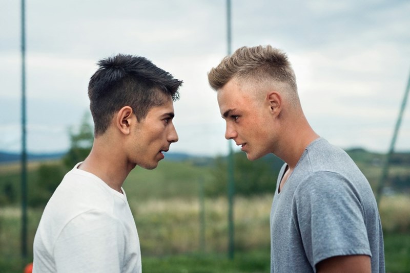 Two young men facing off in a tense confrontation outdoors during a personal conflict