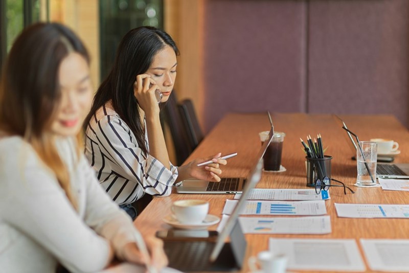 Woman on a call while sitting in office room with other employees