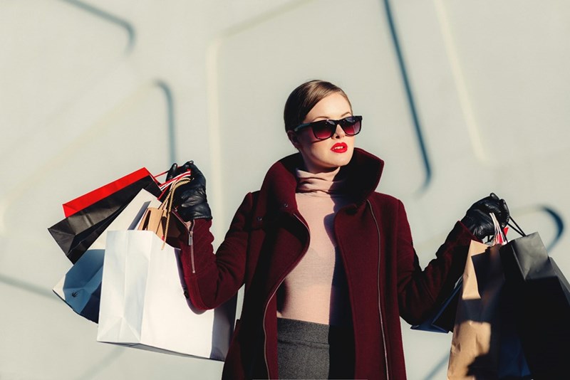 Woman holding black and white paper bags after going on a shopping spree