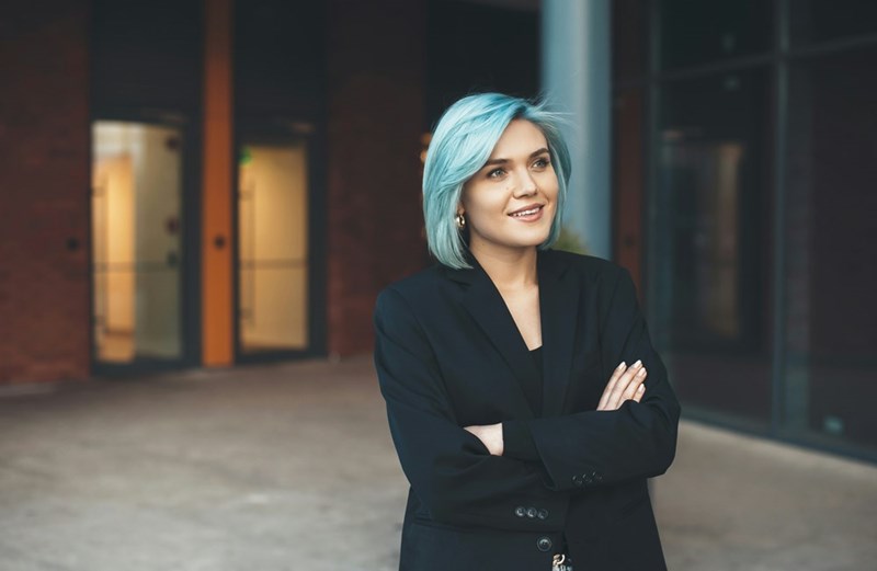 A woman wearing a blazer stands in an office building