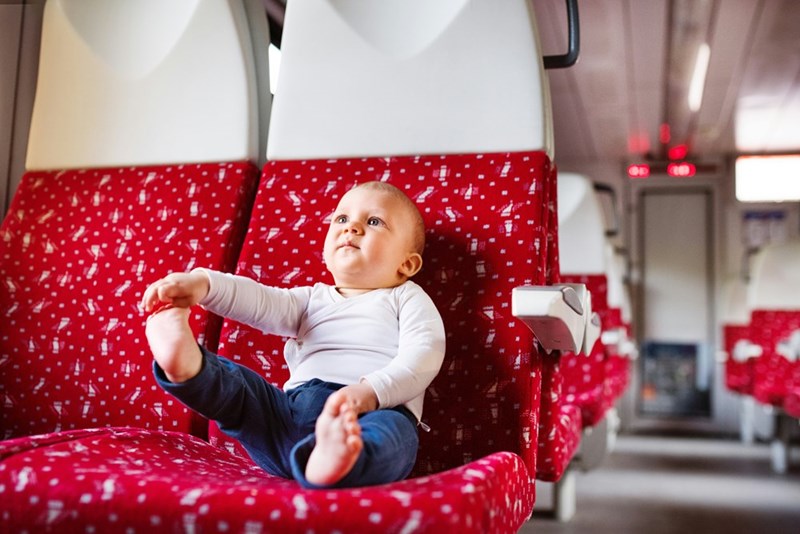 Baby sits on airplane seat.