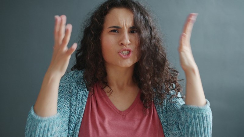 Woman with curly hair looking angry and frustrated