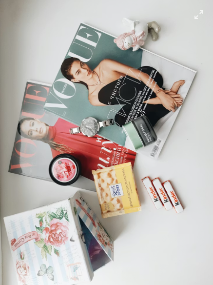 Two vogue magazine covers laying in a white table surrounded by free samples of different kinds.