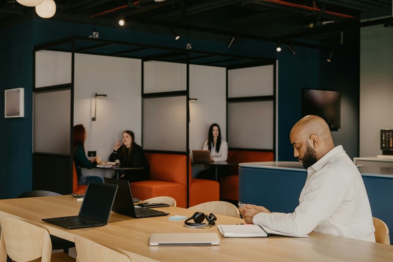 An employee sits alone at a desk in a coworking space.