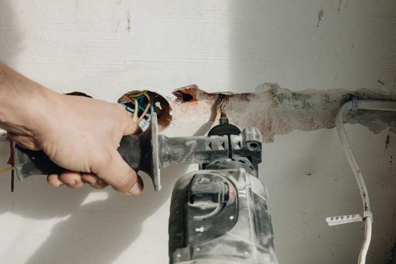 A technician drills through drywall on a work site