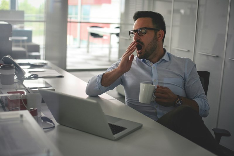 Businessman yawning on an office desk