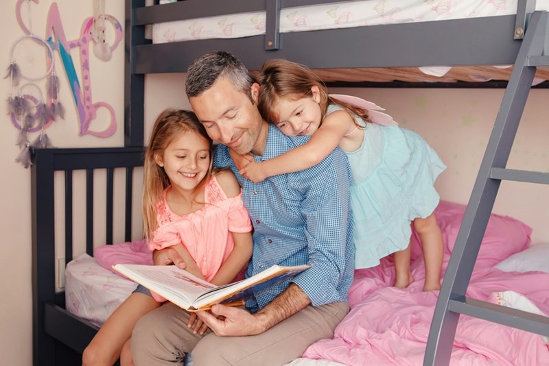 Dad reads a book to 2 daughters. 