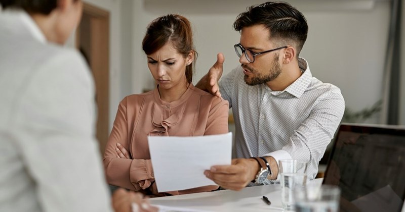 A couple argues as they review a document about needing to repay a loan.
