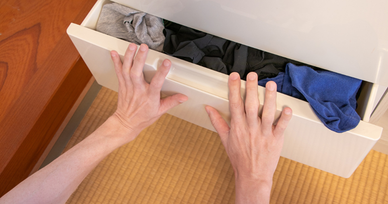 Pushing clothes into the drawer of a dresser