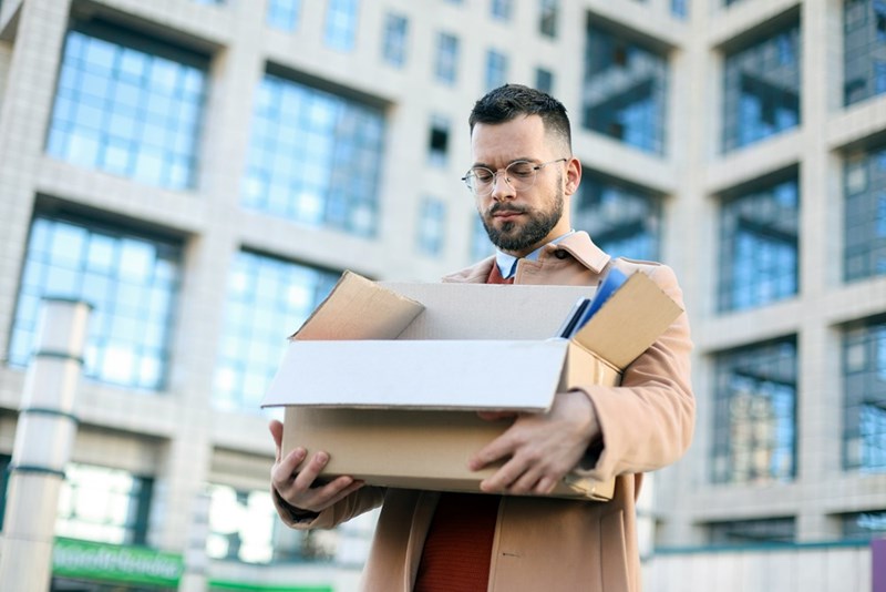 Man leaves an office building with his belongings after quitting