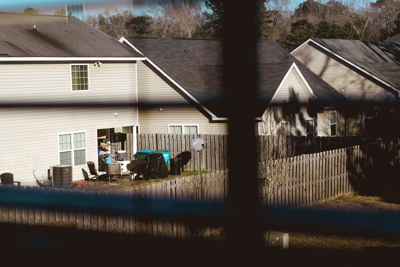 Two house backyards separated by a wood fence.