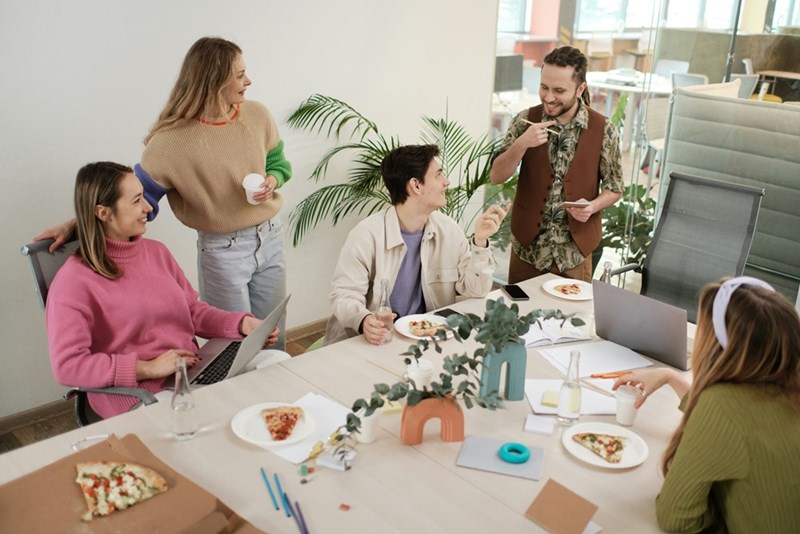 A group of people sitting around a table eating pizzza