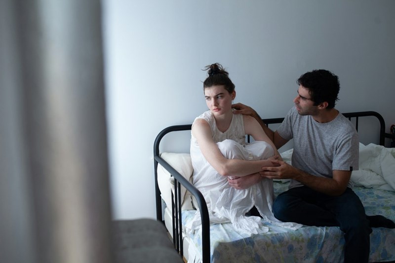 A man sitting next to a woman on a bed