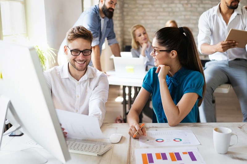 Boss smiles at sales rep as they go over charts together.