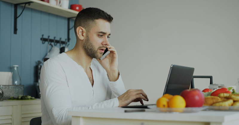 Man Working from Home with Laptop and Phone