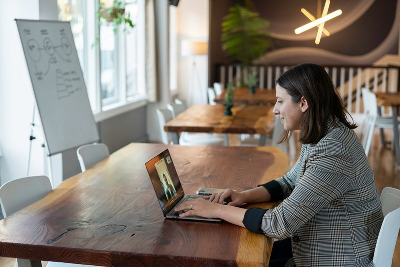 Woman sitting at an open office while on an online meeting.