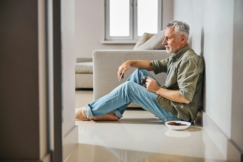 Middle aged man sitting on the floor with a cup of tea and cookies