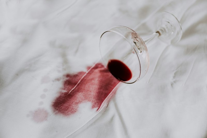 A glass of wine being spilled in a white dress.