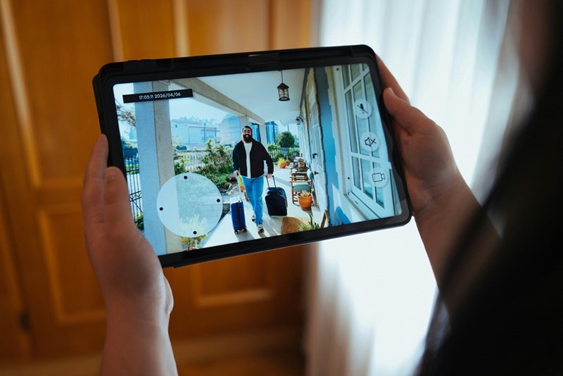 Confused AirBNB guest shows up with suitcases, ready to enter the wrong home, as homeowner watches through camera.