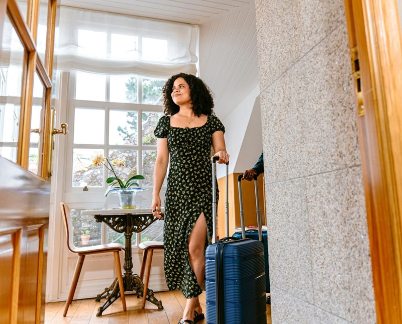 Traveller enters AirBNB with suitcases in hand.