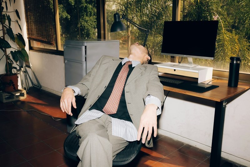 Man in suit slumped in office chair with head back