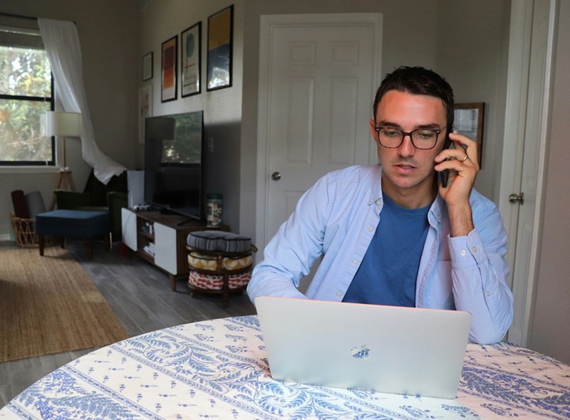 A remote worker takes a call from his kitchen
