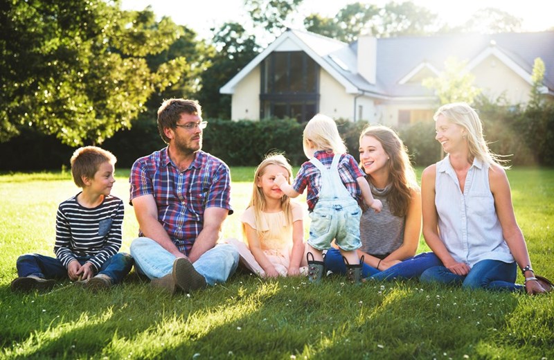 Large family with lots of siblings sit together outdoors.