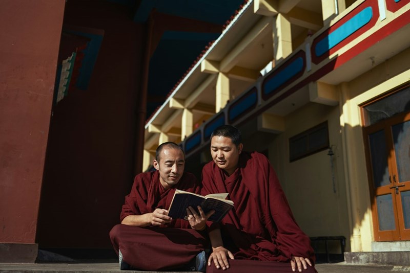 Two monks sitting on steps reading a book