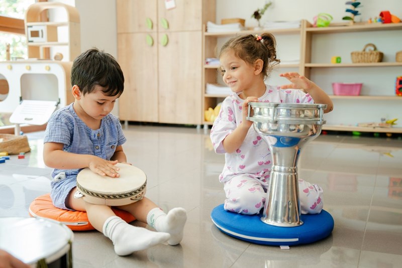 Toddlers playing with instruments in the floor. 