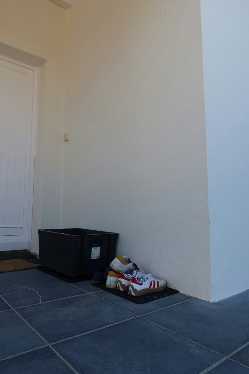 A black bin laying in the porch of a house
