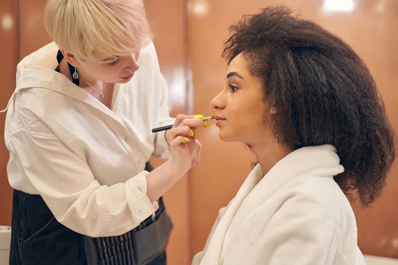 Professional makeup artist applying natural bridal makeup to a woman, highlighting beauty preparation and wedding day styling