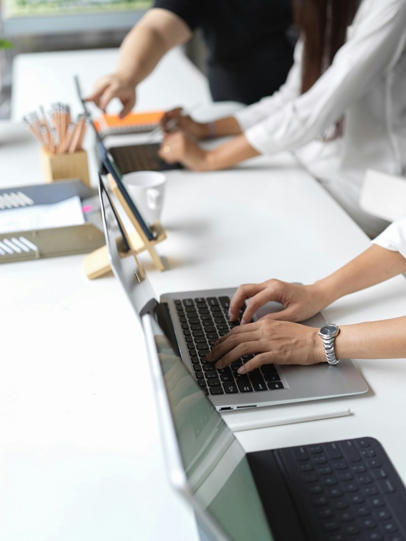Room of tech employees typing on desktop computers and laptop computers