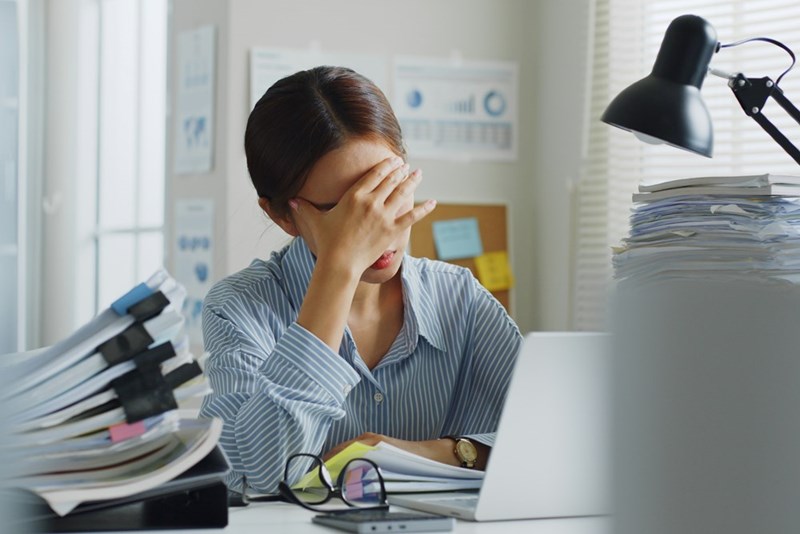 Tired young office employee holding her head in her hand