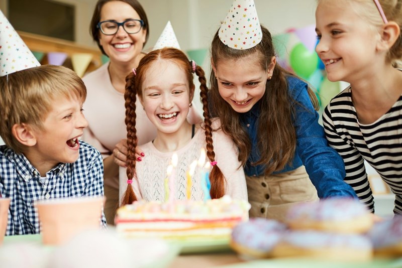 A group of 11-year-olds wears party hats at a birthday celebration.
