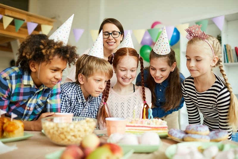 A group of 11-year-olds wears party hats at a birthday celebration.
