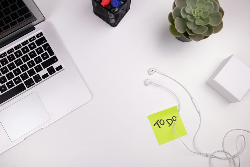 A laptop on a clean desk next to a “to-do” list for daily tasks.