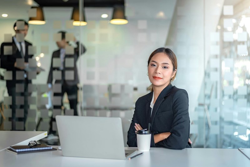 A paralegal folds her arms while sitting at her desk in the office of a law firm.