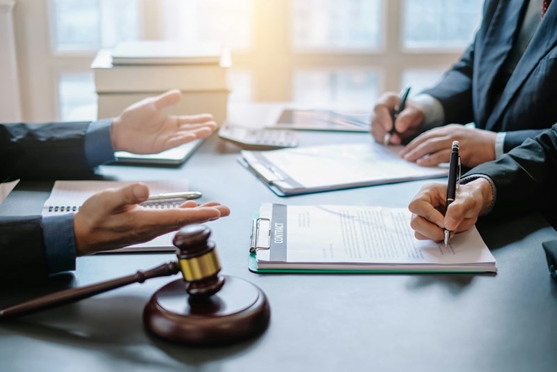 A shot of the hands of lawyers and clients arguing across a table in a conference room.