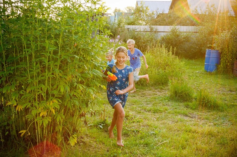 A group of kids plays in the grassy backyard of a neighboring homeowner.