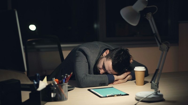 Employee working long hours sleeps at his desk.