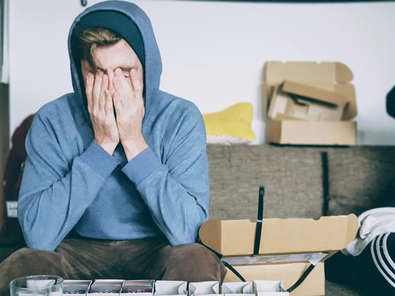 A frustrated tenant sits in his apartment full of boxes
