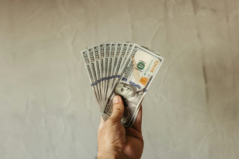 Employee holds a row of $100 bills.