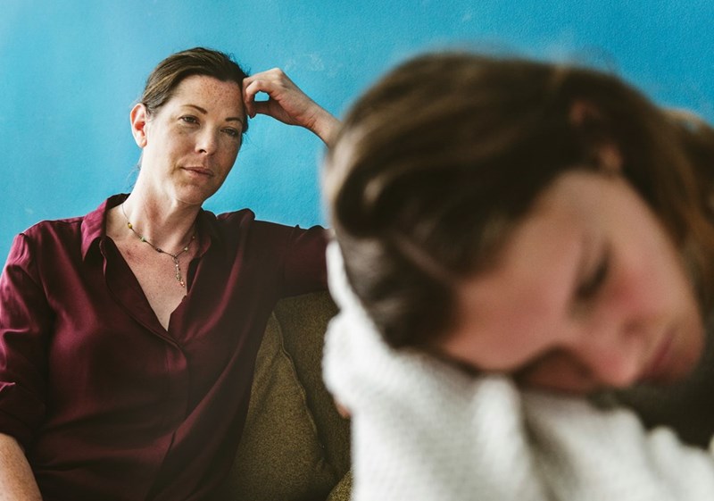 An older woman looks sternly at her stepdaughter.