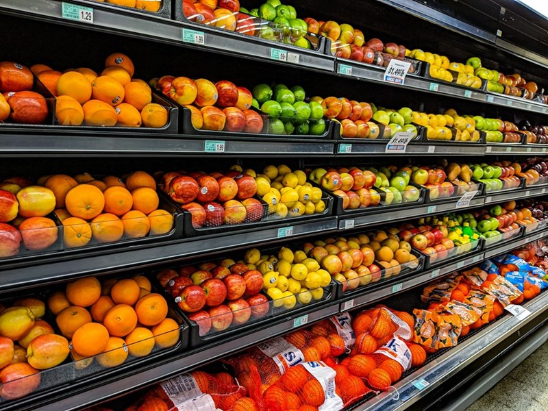 Colorful fruit display in grocery store produce aisle with apples, oranges, and citrus neatly arranged