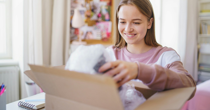 A woman smiles as she opens a cardboard box package