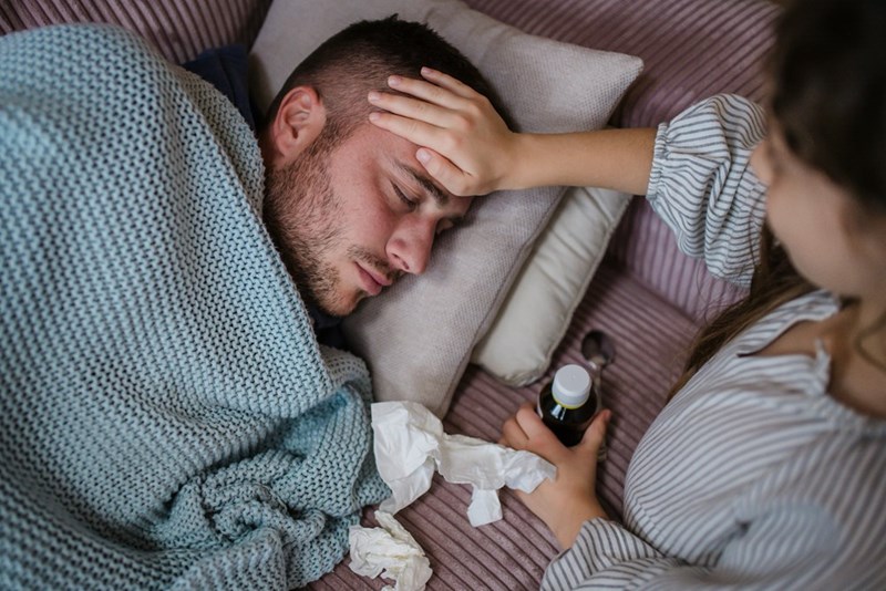 A high angle view of little daughter taking care of her sick father at home