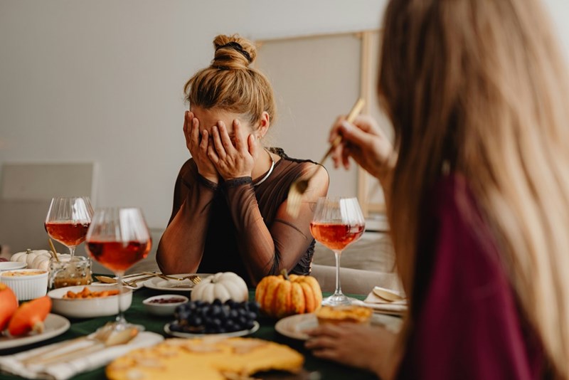 A woman looks stressed at the dinner table