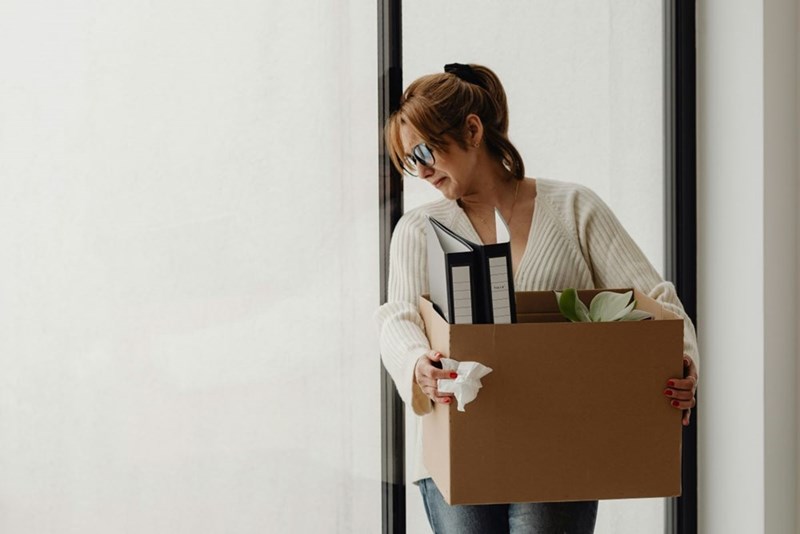 A woman holding a box with a plant in it